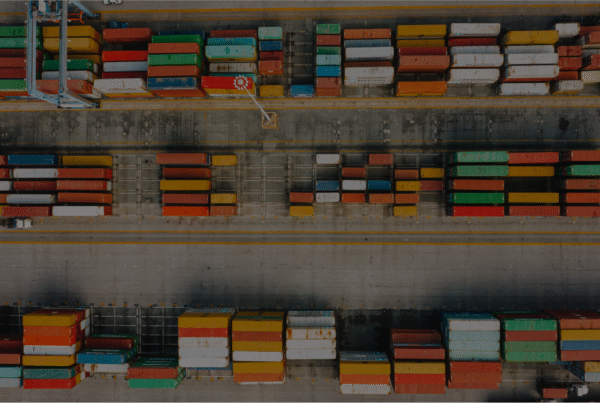 A dock with crates loaded on top of each other. Siemens Opcenter APS specializes in various industries including export/import.