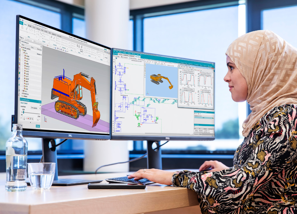 A person sitting at a desk with a dual monitor set-up, using Amesim software