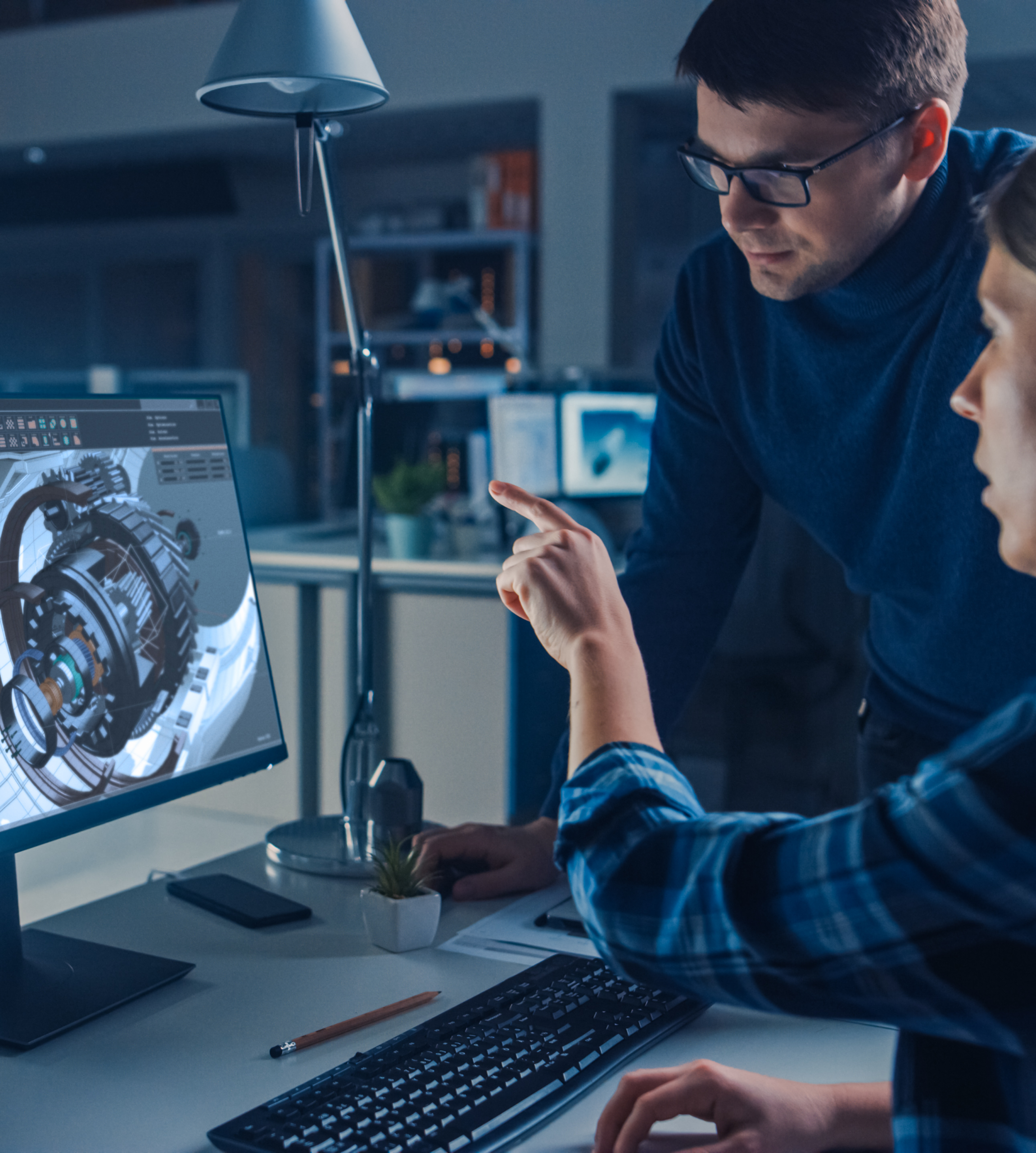 Two people standing around a computer discussing the CAD Model on screen.